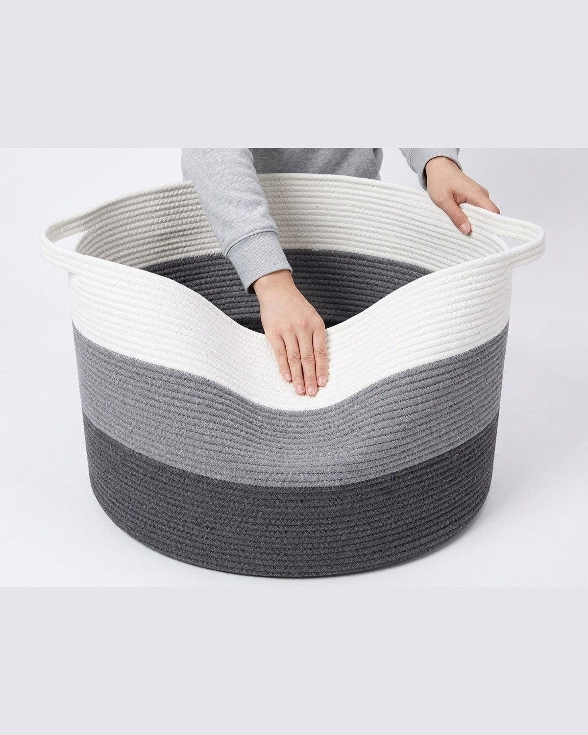 Hands pushing a folded cotton rope basket back into shape